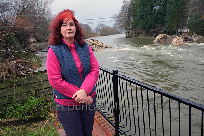 DAMAGE... Mandy Watson, the owner of Pooley Bridge Post Office, at the bottom of her garden in front of what remains of the road bridge...