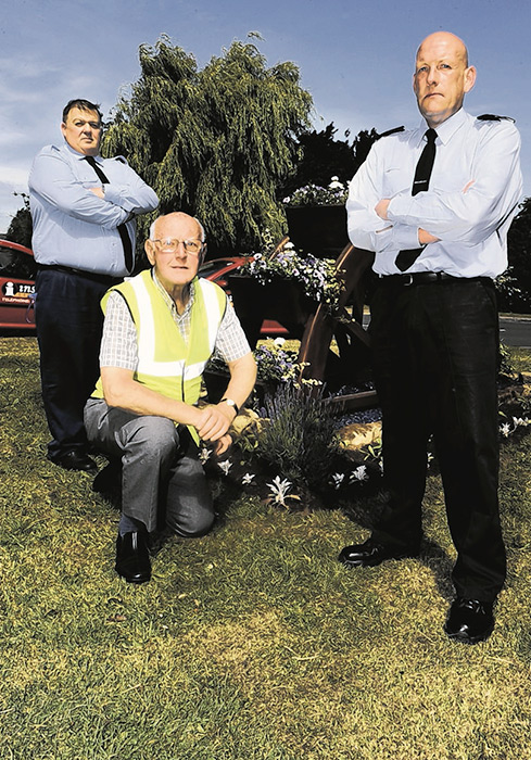 INSTORE SECURITY GUARDS... Malcolm Williamson and Steve Longbottom, with Cayton in Bloom chairman Les Hutchinson. They will be guarding the village flowerbeds following vandal attacks. They are pictured at the ‘water wheel’ display, which was damaged with chemicals...
