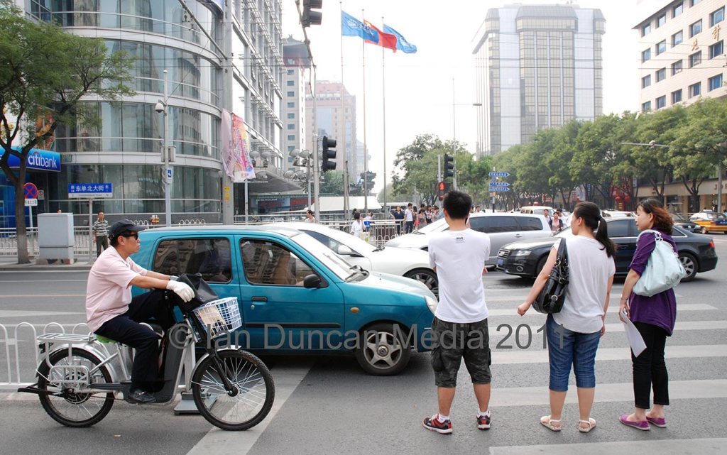 AROUND BEIJING… Pedestrians wait to cross the road in Beijing in China…