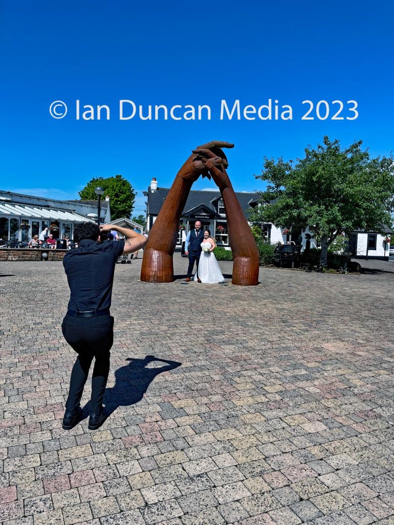 Wedding photographer in action in front of The Big Dance Sculpture by artist Ray Lonsdale in Gretna Green in Scotland. Photo: Ian Duncan.
